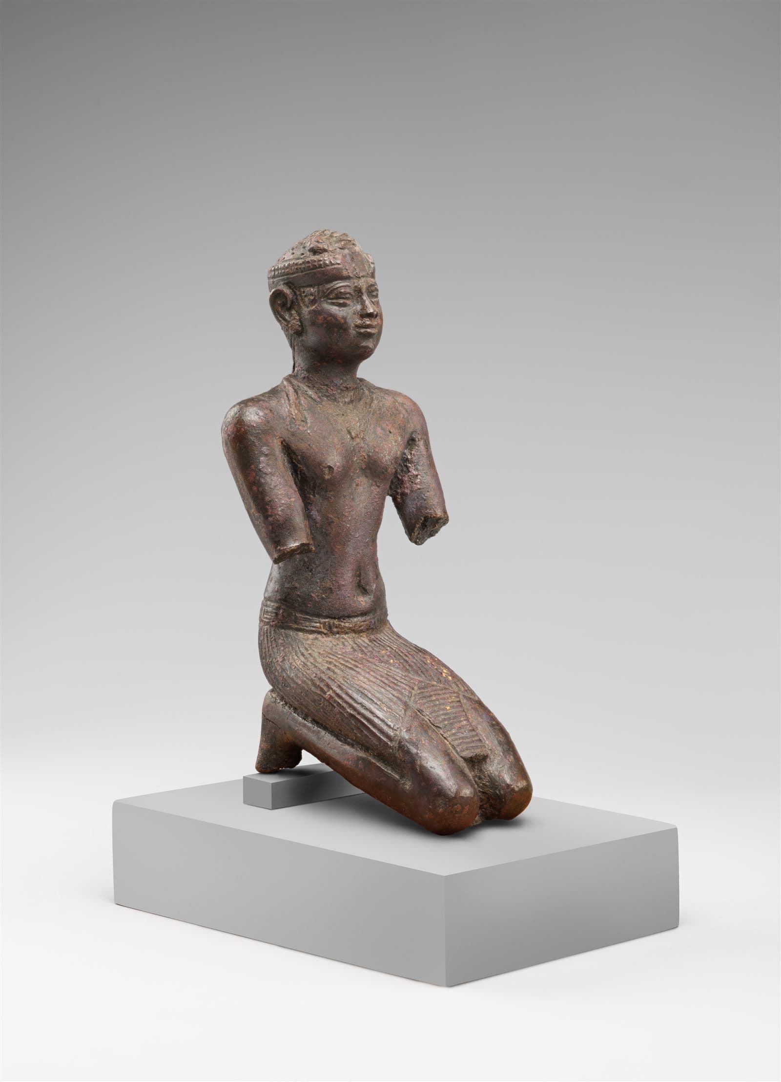Ancient stone statue of a kneeling Kushite king, arms extended, wearing the close-fitting cap-crown of the Twenty-Fifth Dynasty.