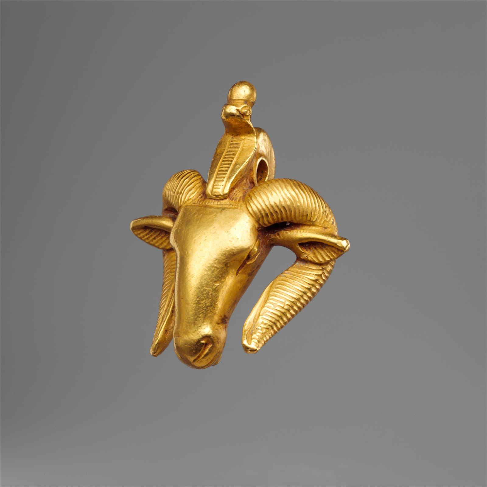 Gold ram's-head amulet with a sun disc between the horns, Kushite workmanship.