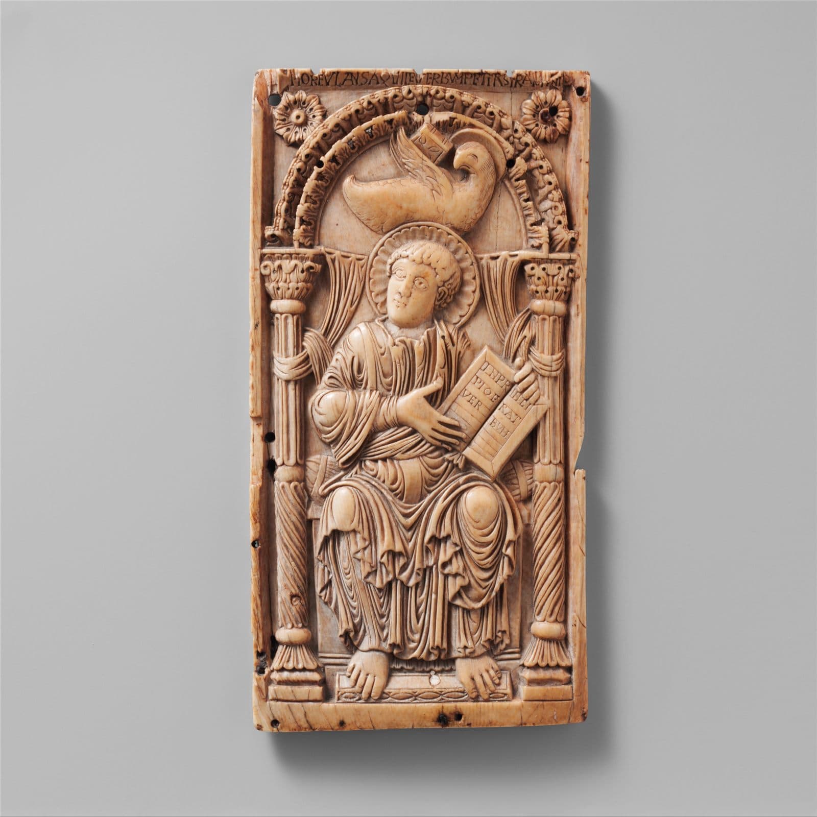 Carved ivory plaque of Saint John the Evangelist seated writing, his eagle above him.